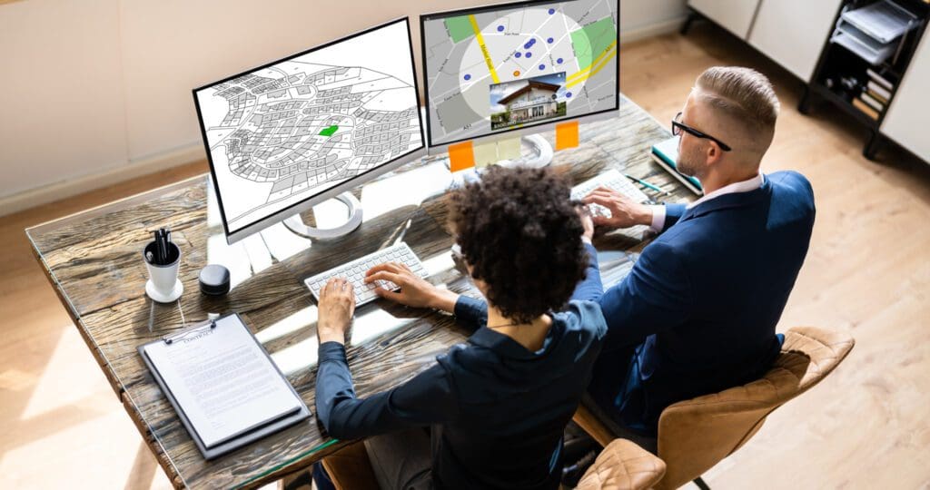 Two people working with dual monitors.