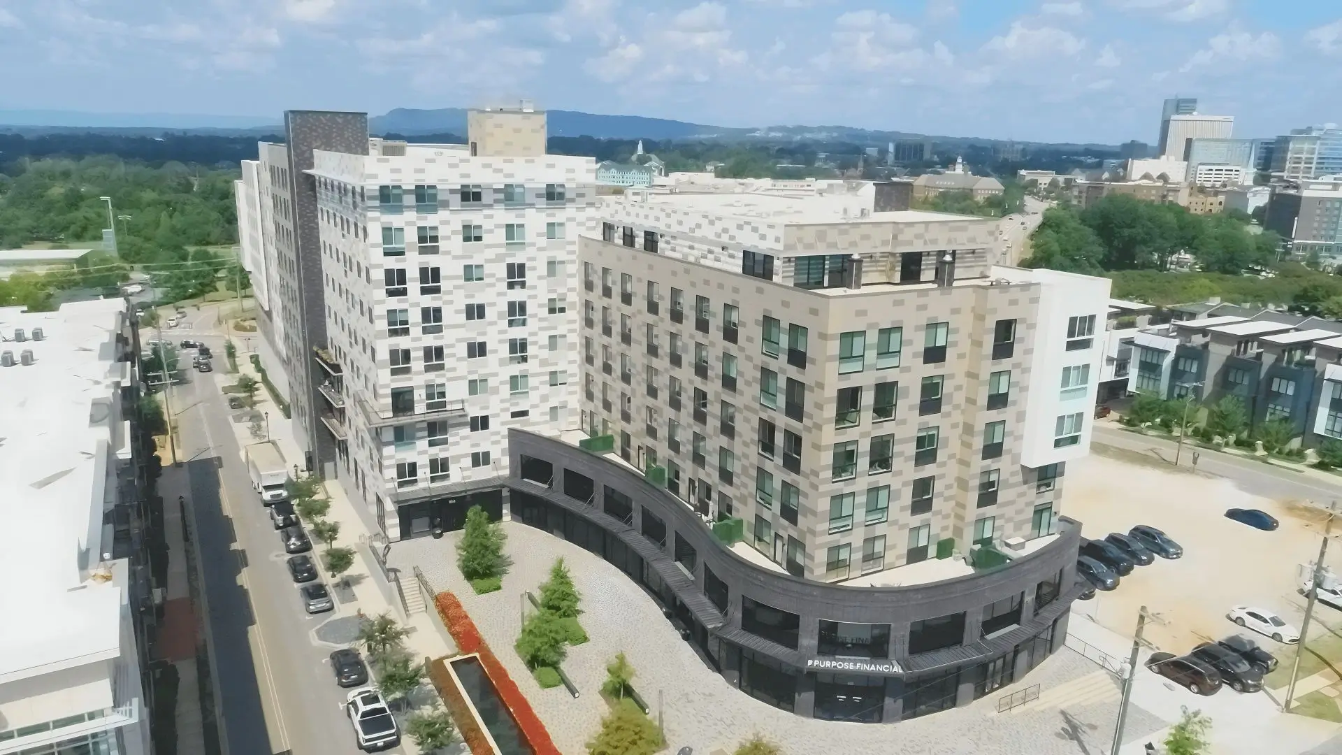 Aerial view of The McClaren mixed-use development in Greenville, SC, featuring modern residential buildings, retail space, and surrounding city skyline.
