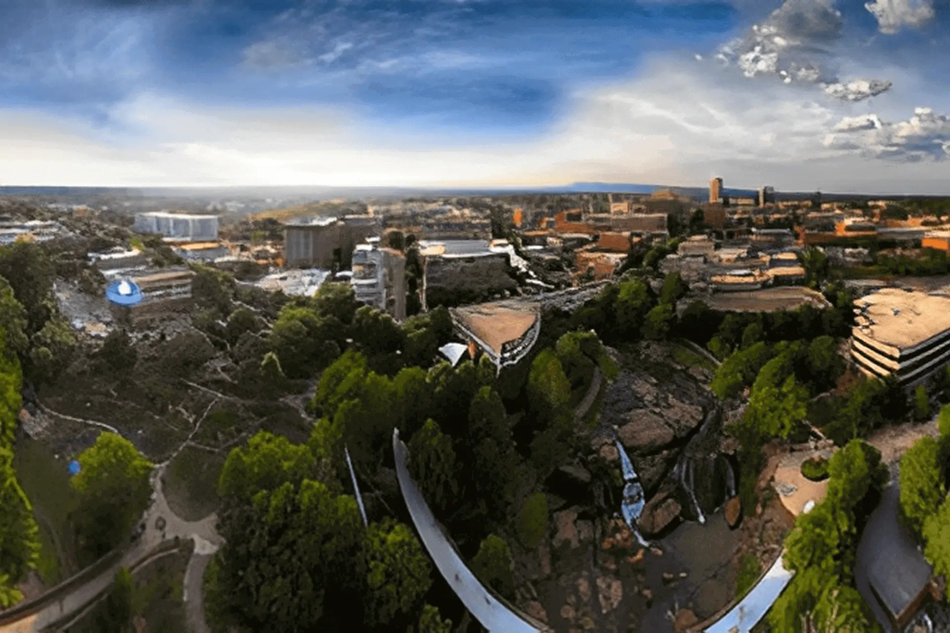 A panoramic cityscape with lush greenery and a dramatic sky.