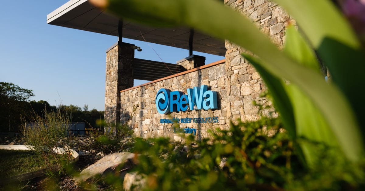 Stone building with ReWa logo and plants.