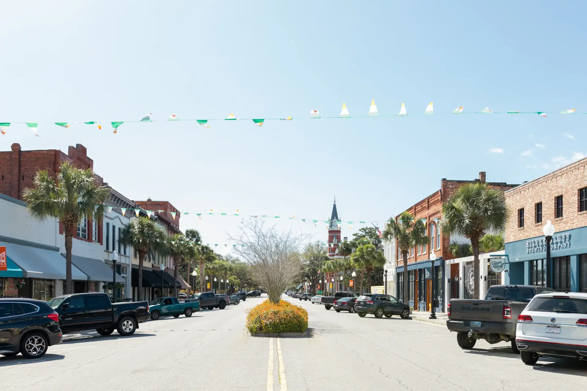Small-town street with parked cars and banners.